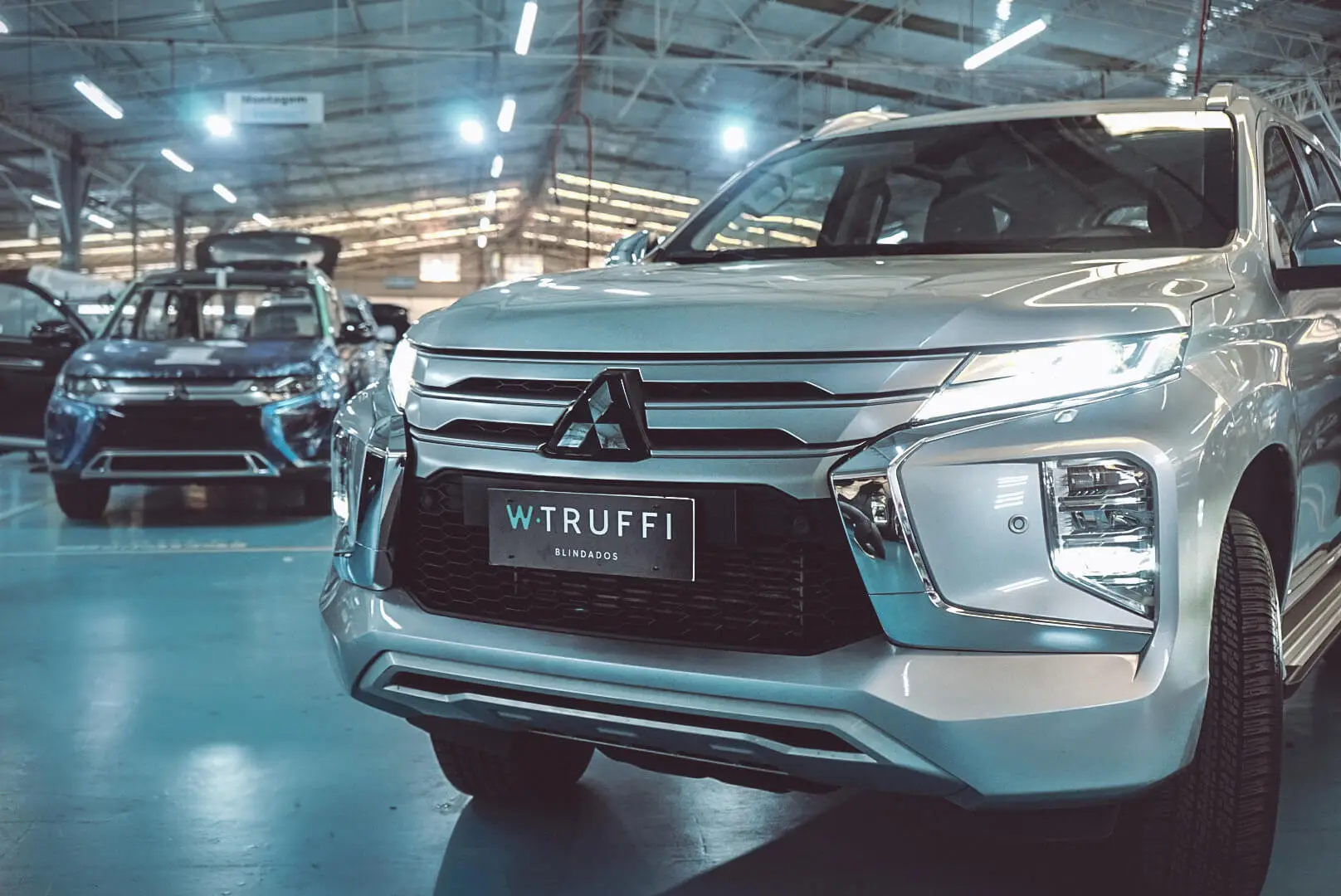 Carro da Mitsubishi em uma grande garagem com uma placa da W. Truffi blindados